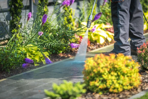 Person reinigt Pflasterweg mit Hochdruckreiniger